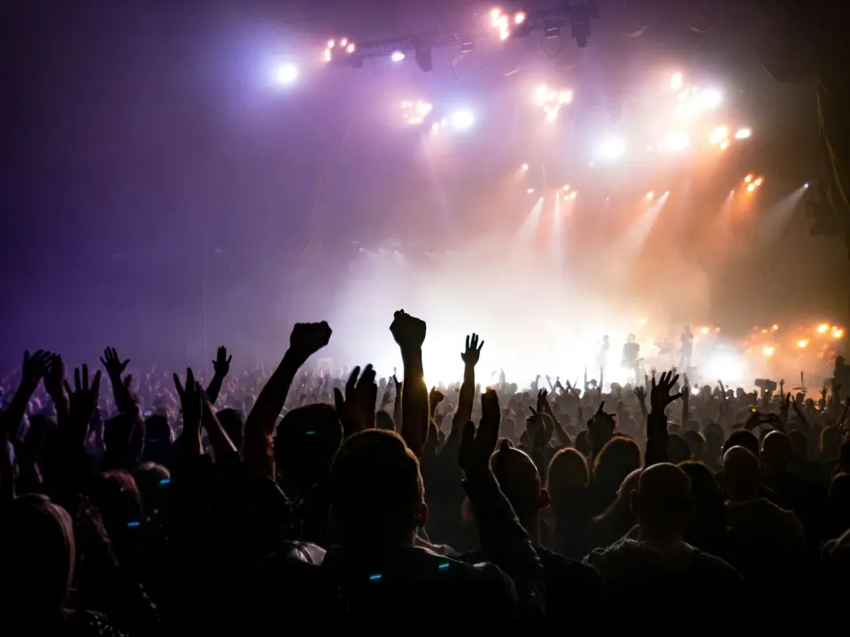 Concert crowd with hands raised under stage lights